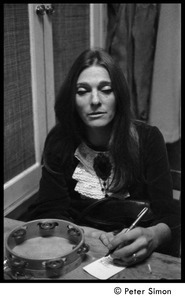 Judy Collins seated with tambourine and pen, behind stage at Electric Circus