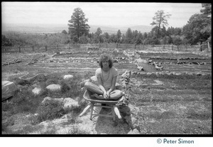 Peter Simon seated in a wheelbarrow in garden plot, Lama Foundation