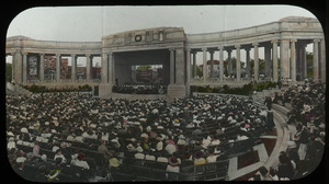 Large crowd seated around stage in an outdoor theater