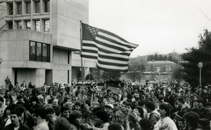 Protesters on UMass Amherst campus, one waving a large American flag