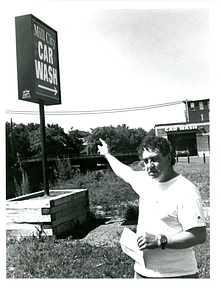 Ed Souza pointing at Mill City Car Wash sign