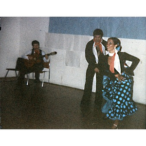 Couple performing a folk dance accompanied by a guitarist.