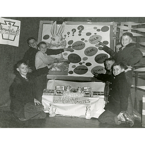 Seven boys pose with an Easter themed display, including a cache of Easter egg hunt prizes