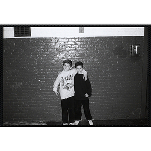 Two boys posing in front of a wall with their arms around each other