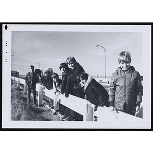 A group of boys pose next to a guardrail along a road