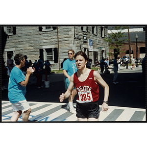 A woman finishes the Battle of Bunker Hill Road Race as a race official cheers her on
