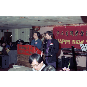 Two women speak from a podium at a gathering of the Chinese Progressive Association to celebrate the Chinese New Year