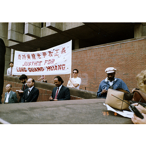 People standing, listening, and taking notes at the rally for Long Guang Huang in City Hall Plaza in Boston