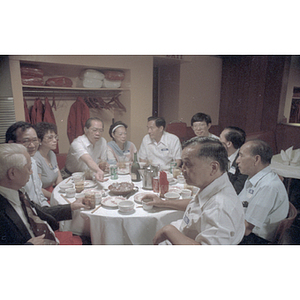 Members of the Chinese Progressive Association sit and eat food around a circular table at a welcome dinner held for the visit of Chinese Ambassador Zhang Wenjin to Boston