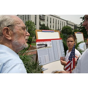 Three people look at the plans for the Veterans Memorial at the groundbreaking ceremony