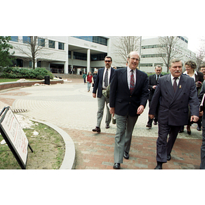Dean Lowndes and Lech Walesa walk with a group through the Snell Library quadrangle