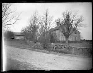 Small shingeld house with stone wall; taken from road