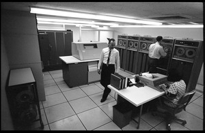 Computer room scene: woman entering data into a console with Honeywell Model 400 mainframe and printer in background