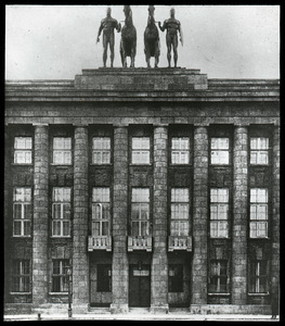 Imposing building surmounted by statues of men leading horses