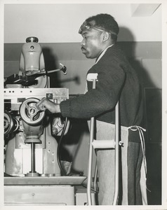 Man using crutches in machine shop