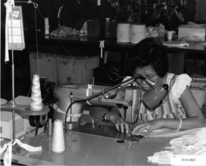 Photograph of a woman using a sewing machine, [1982-1983].