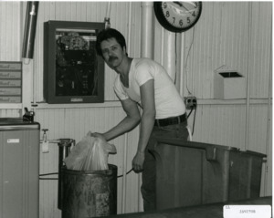 Photograph of a man handling a garbage bag, [1982-1983].