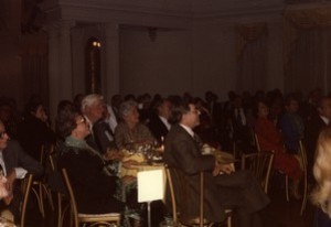 Large room of people seated at tables, Thomas P. O'Neill at center