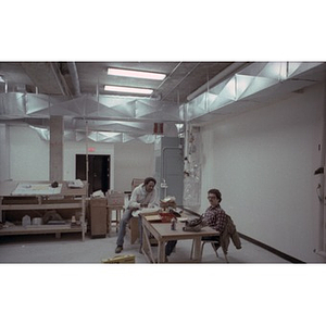 Two construction workers take a break in a makeshift office.