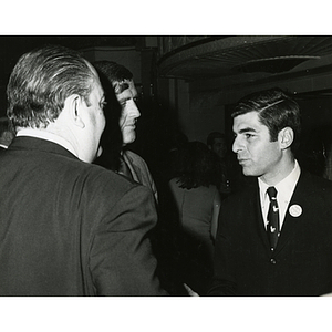 Former Massachusetts Governor Michael S. Dukakis talking with Frederick J. Davis, at center, and an unidentified man during a Boys' Club meeting