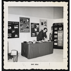 A male staff member sets up an information table at the Boys' Clubs of Boston Art Exhibit