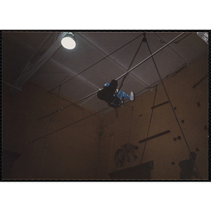 A child walks sideways on a rope in a gymnasium