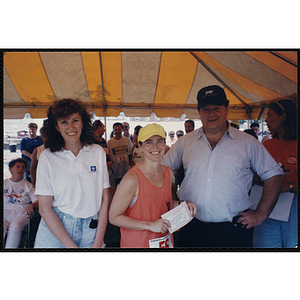 A runner, woman, and man pose with a gift certificate during the Bunker Hill Road Race