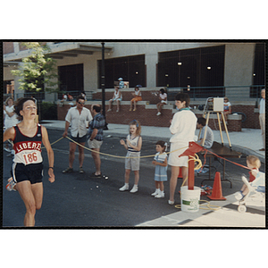 A woman runs past spectators during the Battle of Bunker Hill Road Race