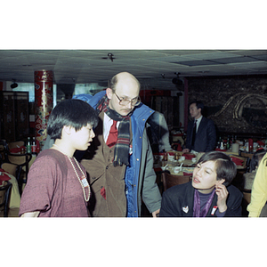 Lydia Lowe chats with a man and a woman beside a restaurant table at a celebration of the Chinese New Year