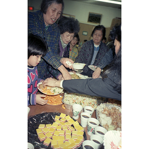 Women and children serve food at a holiday party for the Chinese Progressive Association