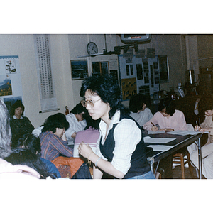 Teacher leans over a seated student during an English class