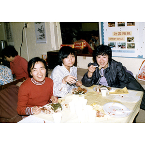 Members of the Chinese Progressive Association eat a Turkey dinner, with three people seated in the foreground