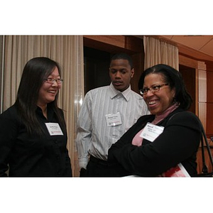 A woman stands with two Torch Scholars at an event