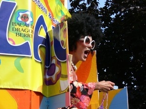 Parade marcher leaning out of the side of a vehicle, tossing strings of beads : Provincetown Carnival parade