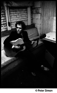 Tim Hardin smoking a cigarette and playing guitar at the Unicorn Coffee House, Boston, Mass.