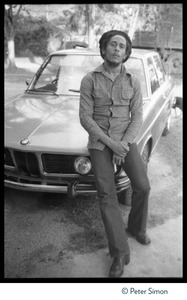 Bob Marley seated on the hood of his BMW at his house in Kingston