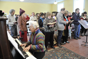 Aftermath of the Congregational Church fire in West Cummington, Mass.: older woman the organ as parishioners sing hymns
