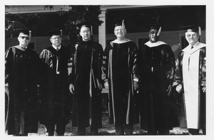 Louis M. Lyons standing outdoors in cap and gown