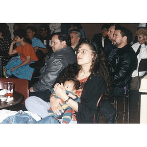 Woman with a baby is among the audience members at an event at the Jorge Hernandez Cultural Center.