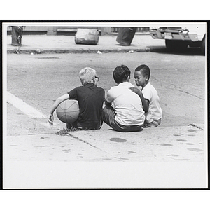 Three Boys and Girls Club members sit outside and talk, one of them holds a basketball