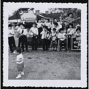 The Bunker Hillbillies perform at an outdoor event with a small child looking on