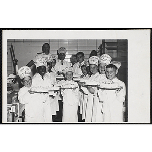 Members of the Tom Pappas Chefs' Club hold decorated cakes and pose with Chefs' Club Committee member Mary A. Sciacca (background, center) in a kitchen
