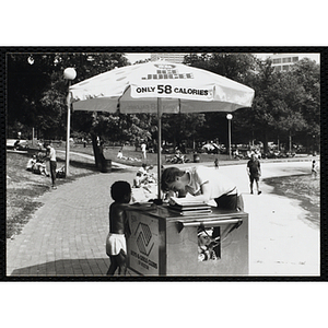 A teenage boy serves ice juice from a food cart to a boy on Boston Common