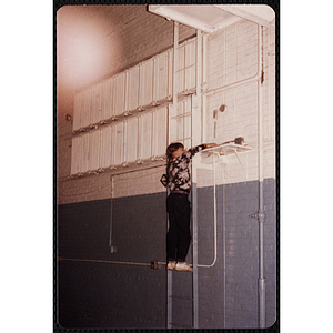 A girl reaches for a shelf on the wall of the Charlestown gymnasium