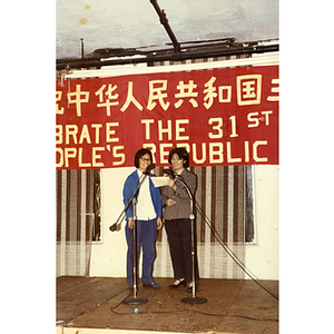 Two Chinese women stand together onstage at the 31st anniversary celebration of the People's Republic of China, held at the Chinese Progressive Association headquarters