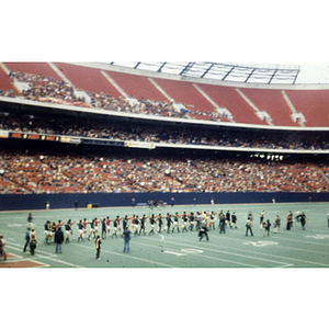 Two soccer teams walk onto the field with hands clasped in the air