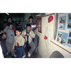 Children try and "pin the tail on the donkey" with balloons, at a Chinese Progressive Association celebration