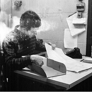 Young man going through papers at a desk at the WNEU studio