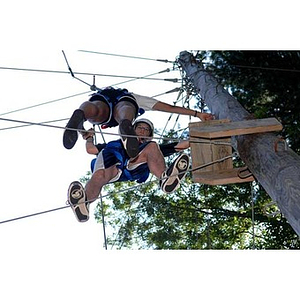 Looking up at two students high up on the Torch Scholars Project Adventure Ropes Course