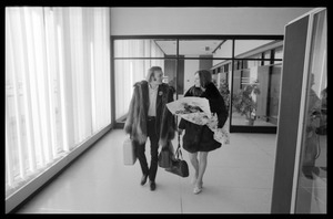 Stephen Stills (in heavy fur coat) and Judy Collins (with a bouquet of roses) walking through an airport